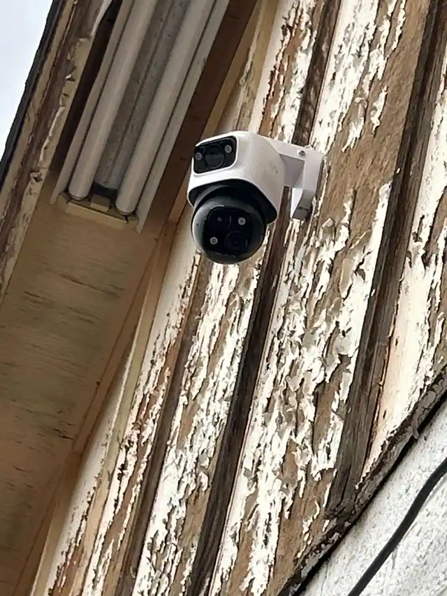 Dual-lens camera mounted to exterior siding